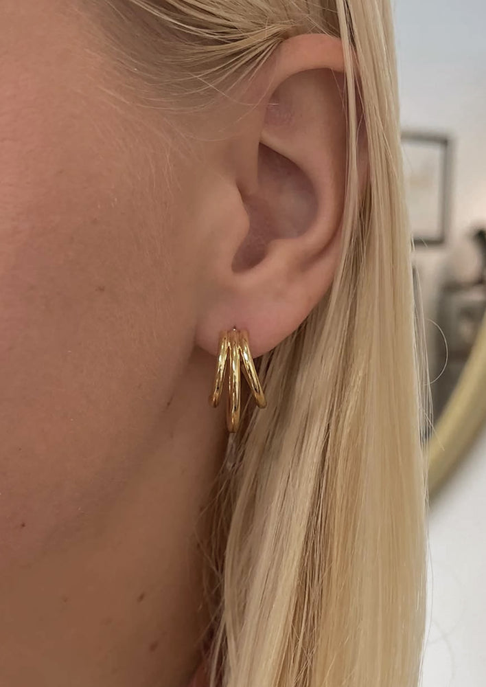 A pair of gold triple hoop earrings.