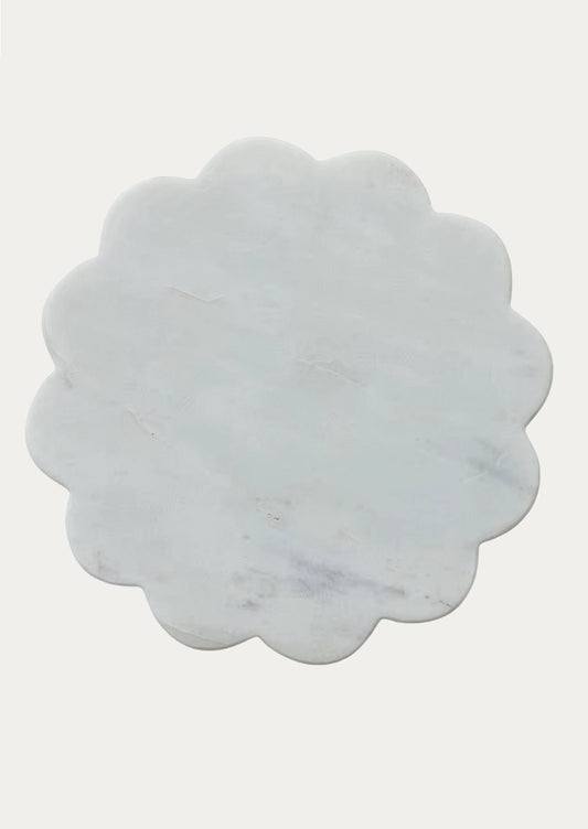 A scalloped-edge round marble trivet in a pale gray-white tone with subtle natural veining.