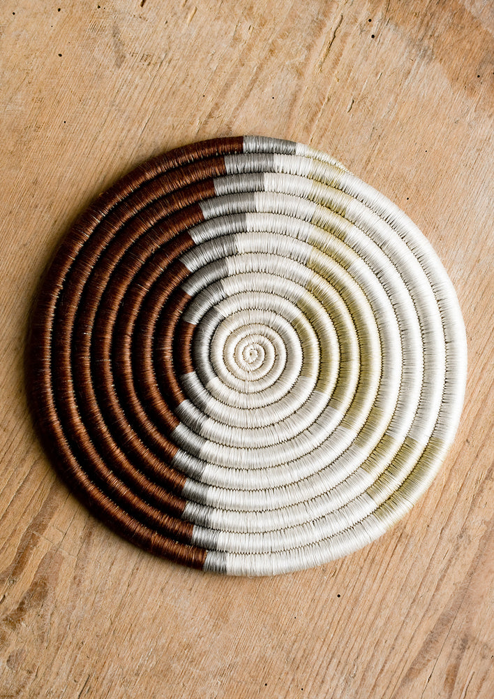 Brown / Grey / Sand: A woven sweetgrass trivet with geometric pattern in brown, grey, white and tan.