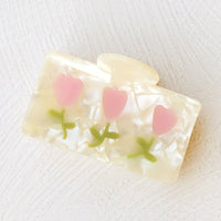 1: A rectangular hair claw with pearl finish with pink tulip design.