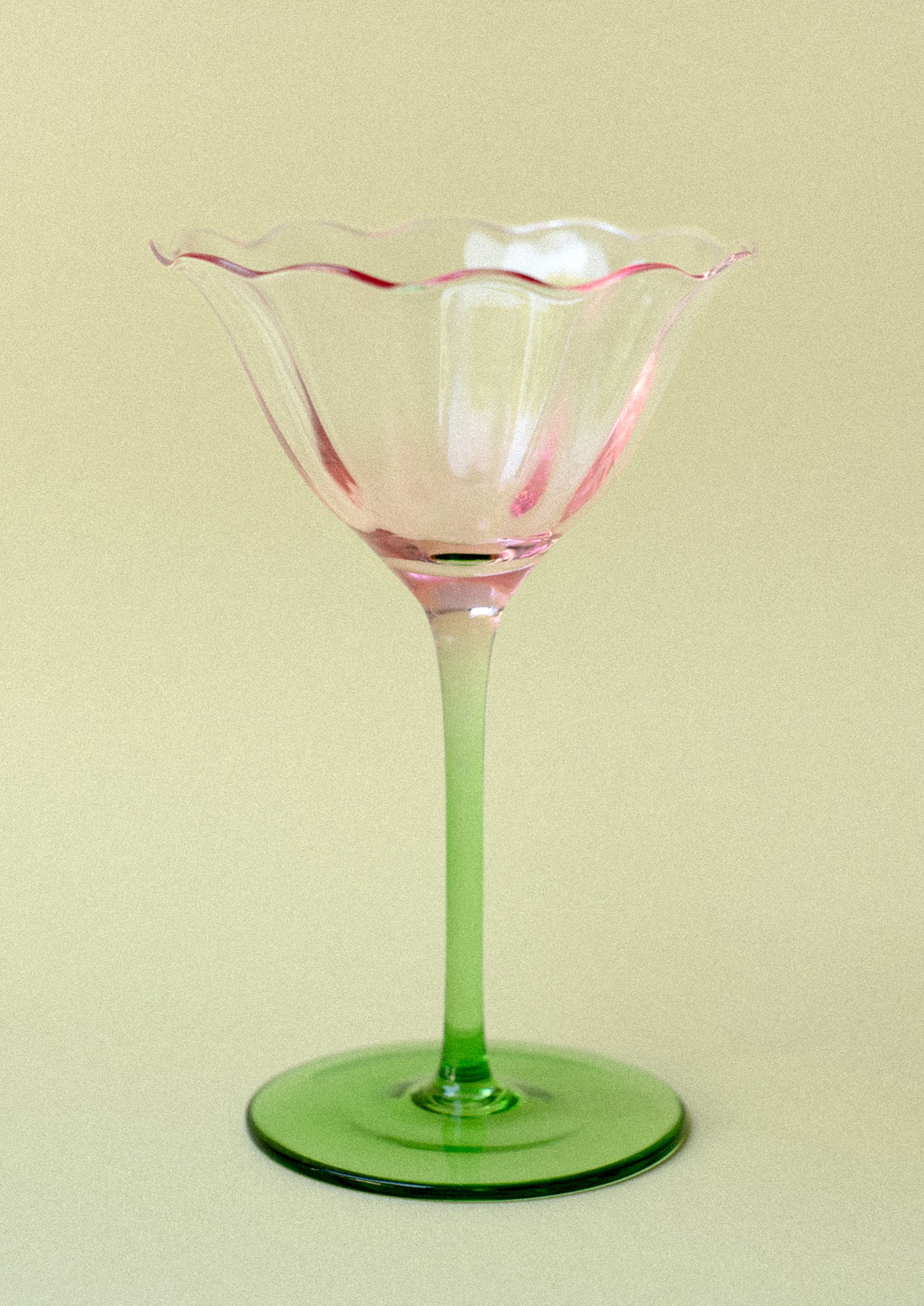 A coupe glass in shape of tulip with pink top and green bottom.