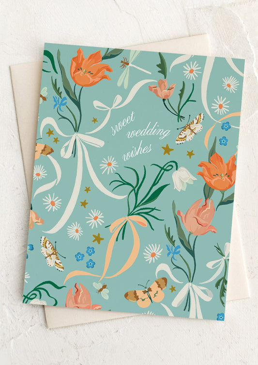 Greeting card with floral design and 'sweet wedding wishes' text on a light blue background.