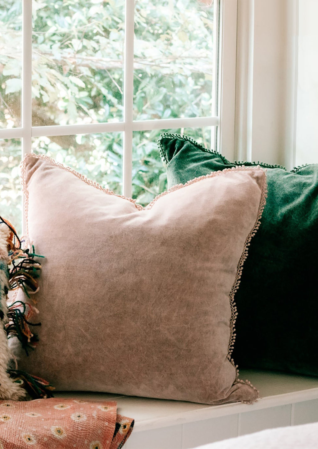 Emerald: Pink and green velvet throw pillows on a window ledge.