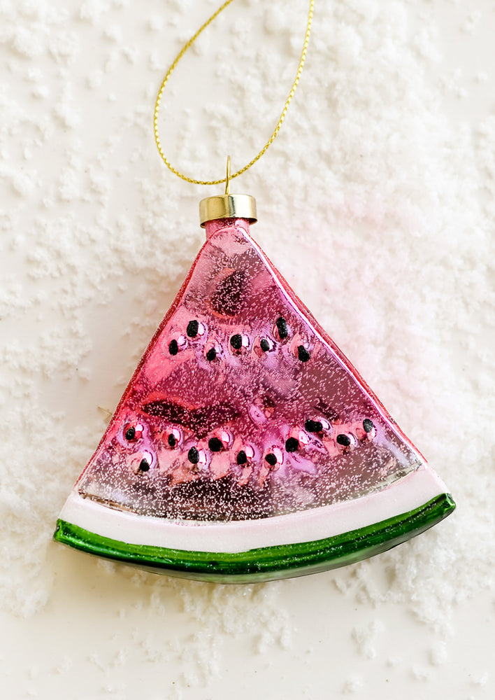 A decorative glass holiday ornament of a triangular slice of watermelon.