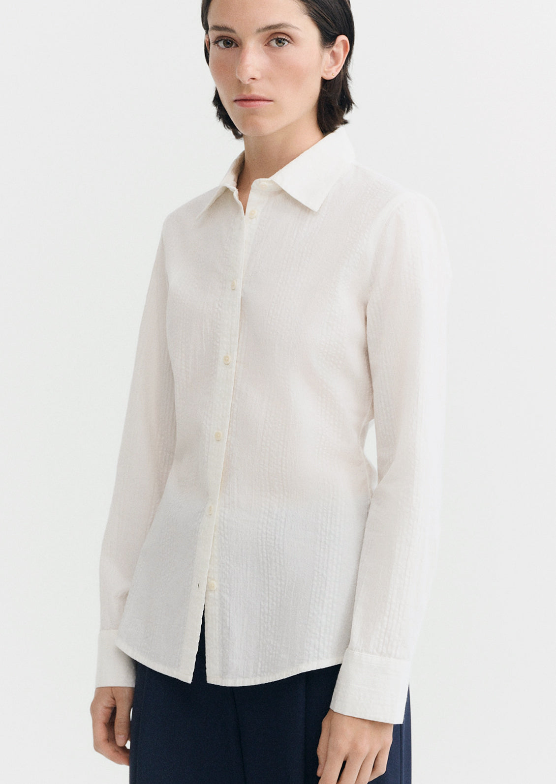 A person wearing a cotton button up shirt with tonal texture.