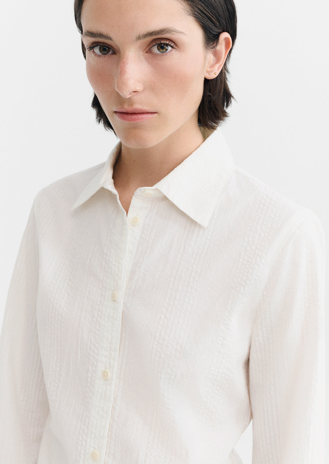 A person wearing a cotton button up shirt with tonal texture.