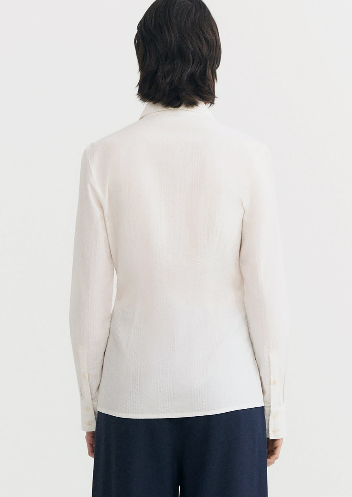 A person wearing a cotton button up shirt with tonal texture.