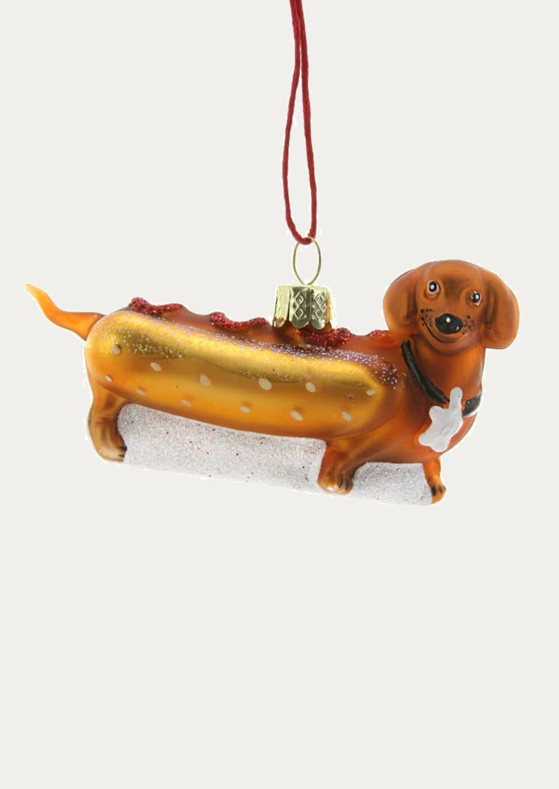 A glass ornament depicting a dachshund dog dressed as a hot dog.