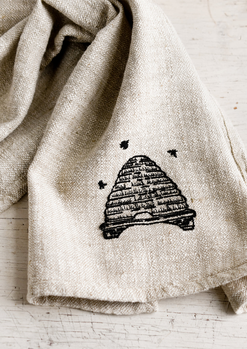 Beehive: A natural linen tea towel embroidered with beehive in black stitching.