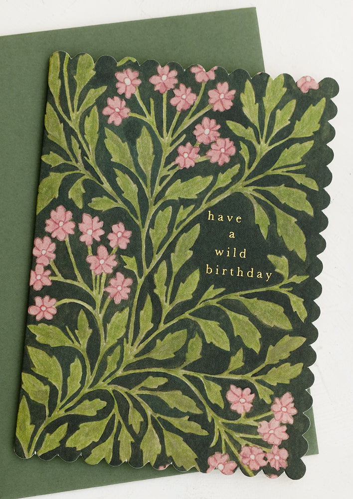 A scalloped edge greeting card with floral on black reading "Have a wild birthday".