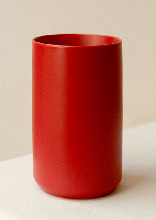 A cylinder shape vase in matte red ceramic.