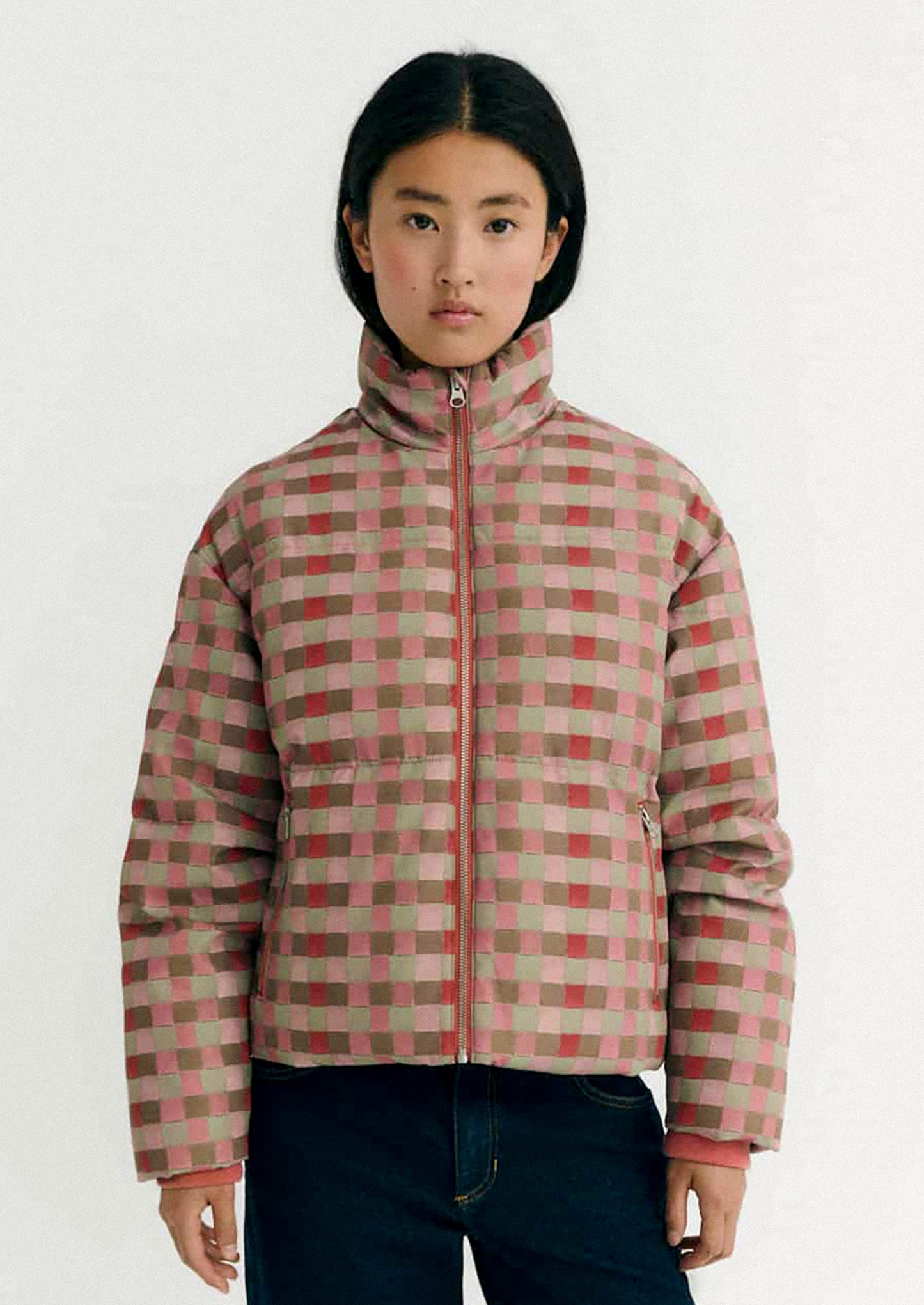 Person wearing a checkered puffer jacket on a white background.