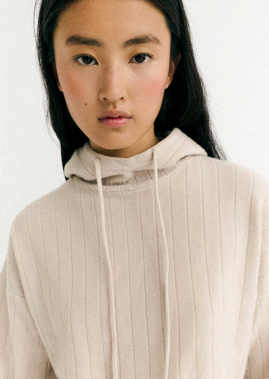 Person wearing a beige hoodie against a white background