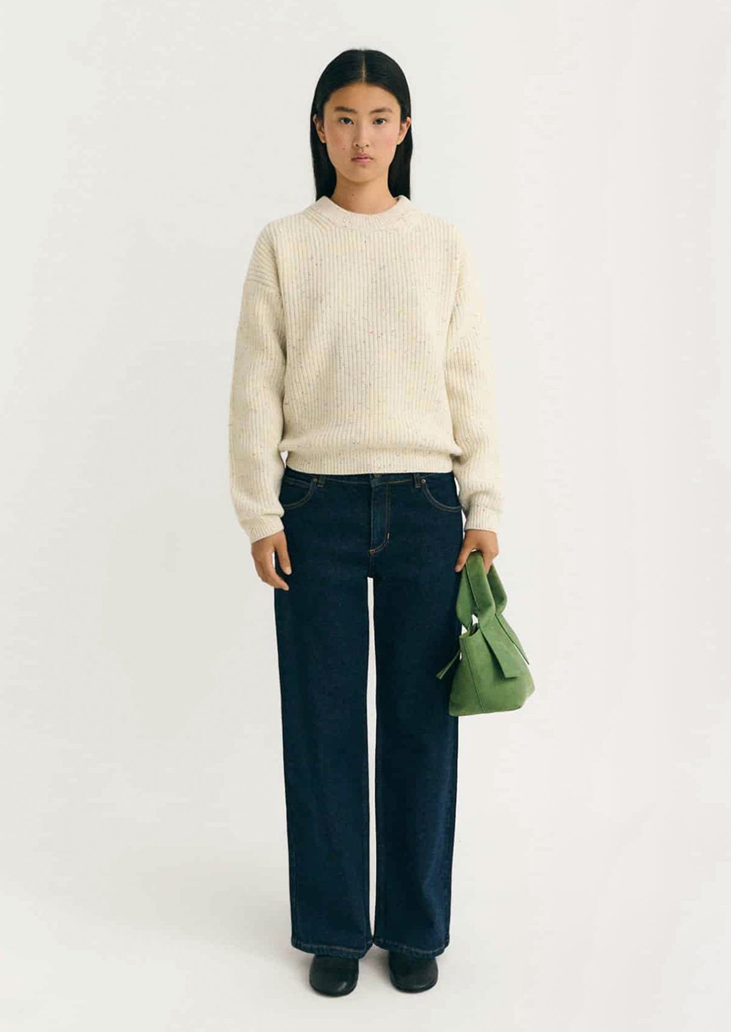 Person wearing a cream ribbed sweater with multicolored speckles.