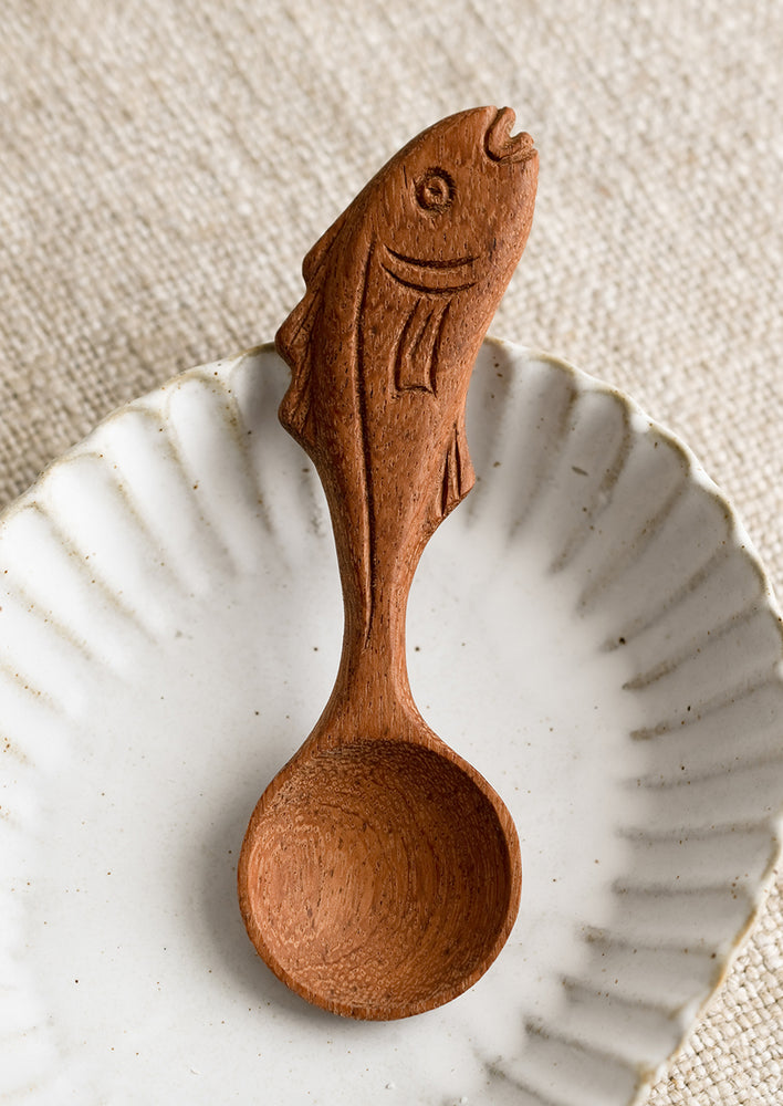 A wooden spoon with a handle carved in the shape of a fish.