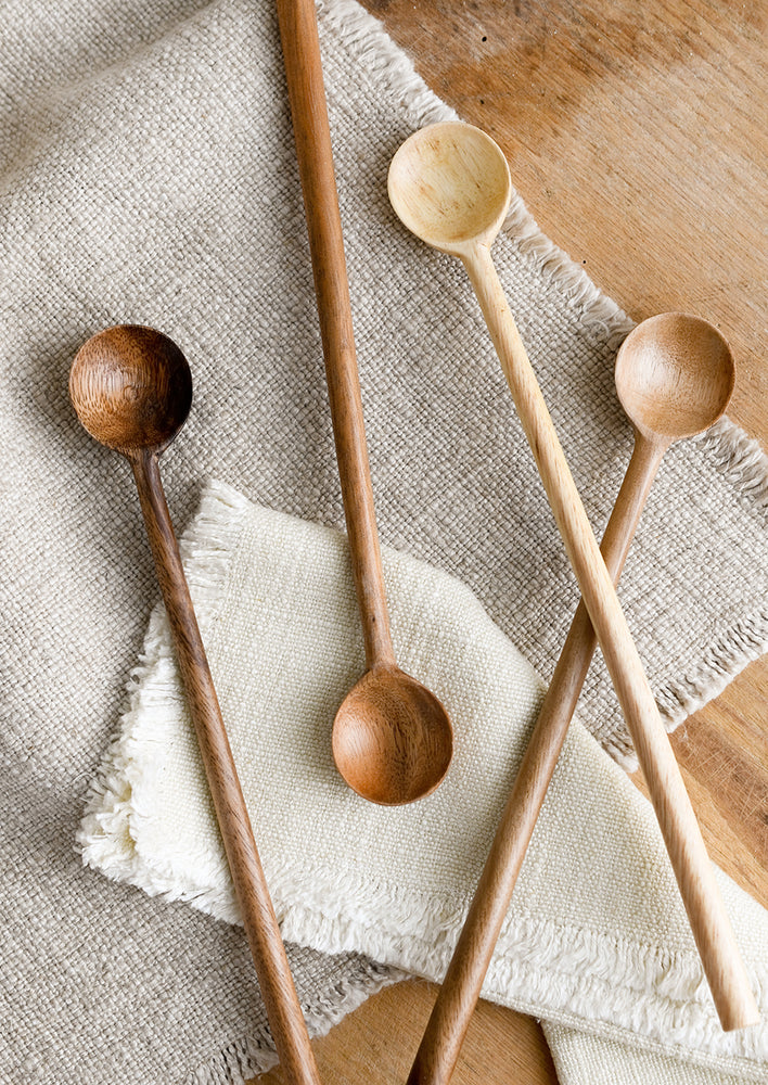 An assortment of wooden tasting spoons with long handles.
