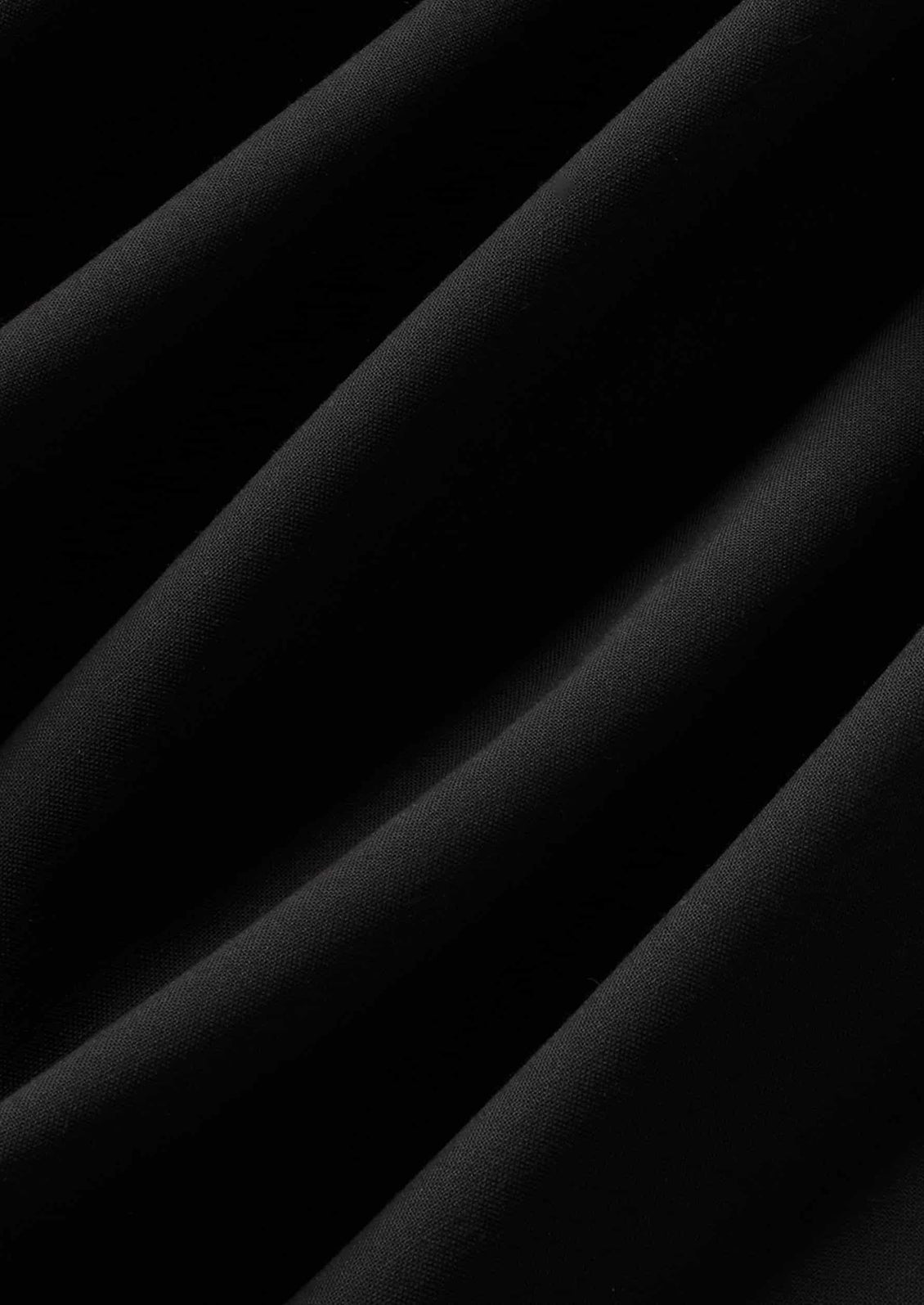 A close-up of draped black fabric with soft diagonal folds and a smooth matte texture.