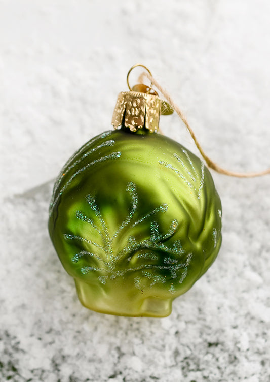 A glass ornament of a single brussel sprout.