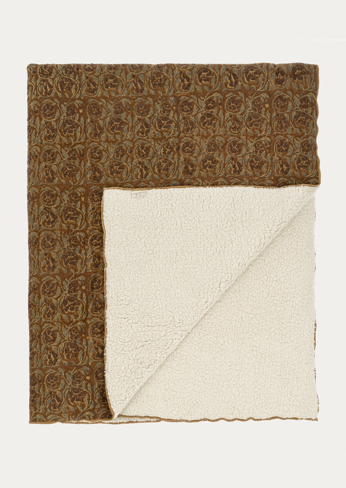 A folded throw blanket with a brown and beige floral patterned woven top and a cream sherpa fleece underside, displayed flat against a light off-white background.