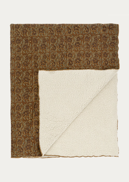 A folded throw blanket with a brown and beige floral patterned woven top and a cream sherpa fleece underside, displayed flat against a light off-white background.