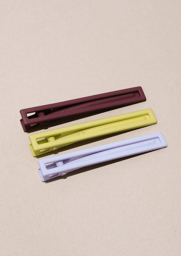 A set of three bar-shaped hair clip sets in yellow, fig and lavender.