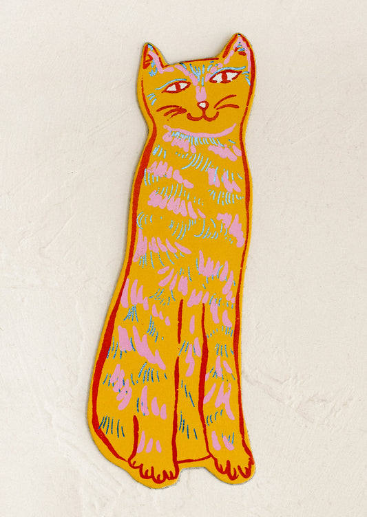 A die-cut leather bookmark in the shape of a cat, in yellow color.