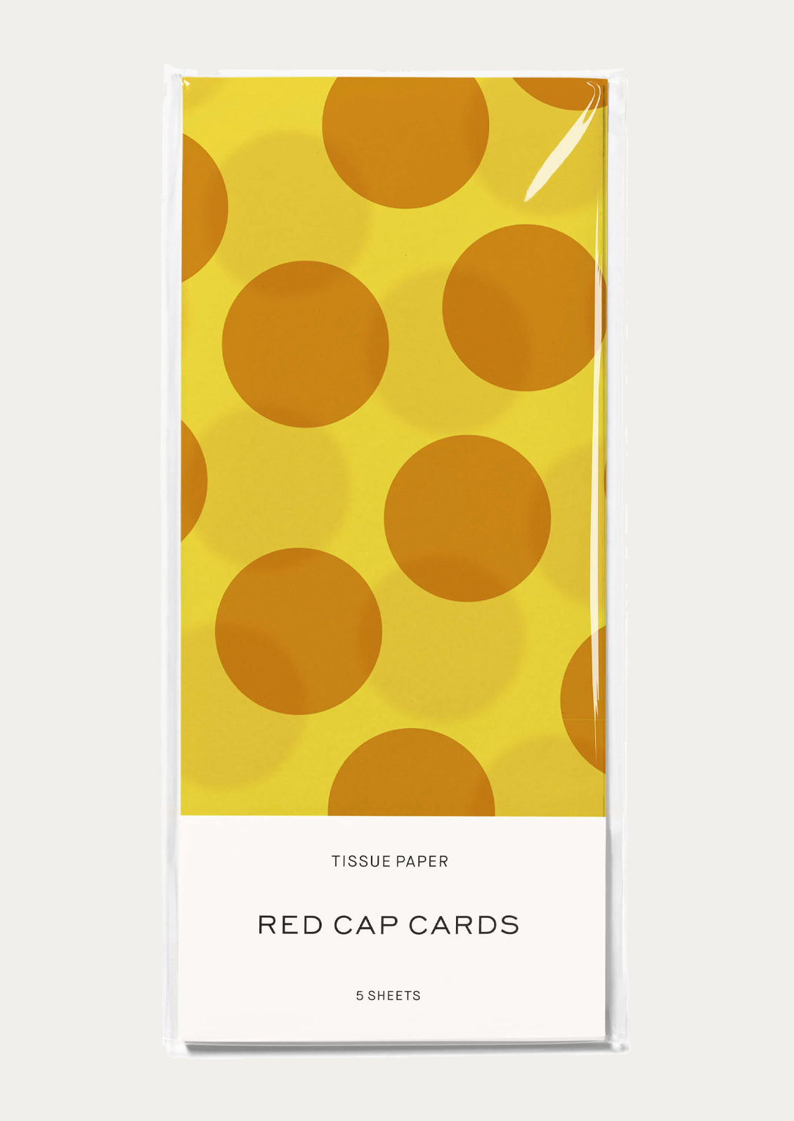 A pack of tissue paper with a yellow background and large mustard polka dots.