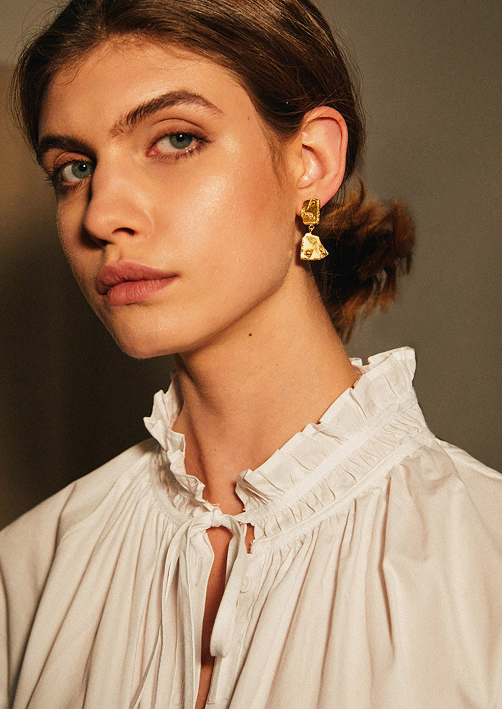 2: A model wearing gold broken tile earrings.