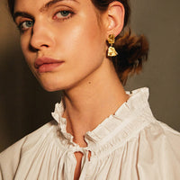2: A model wearing gold broken tile earrings.