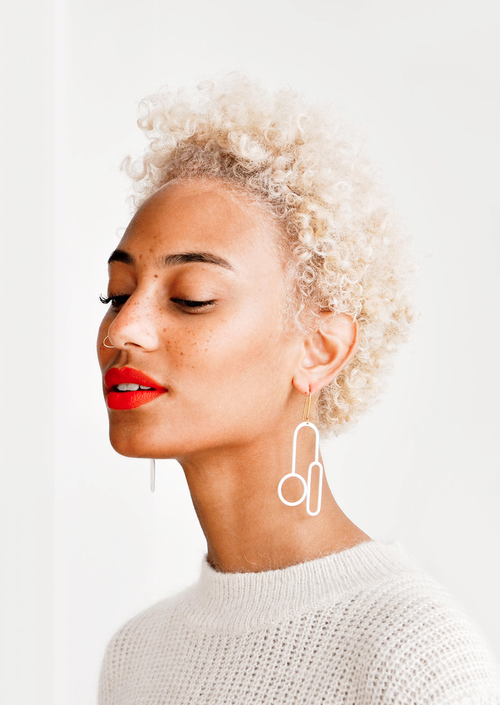 2: Model wears white enamel mixed shape earrings.