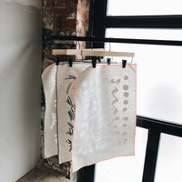 4: Three Patterned Tea Towels Hanging By A Window - LEIF