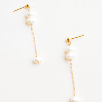 1: A pair of gold earrings with three pearls dangling from a post, and the third pearl is hanging from a fine gold chain.
