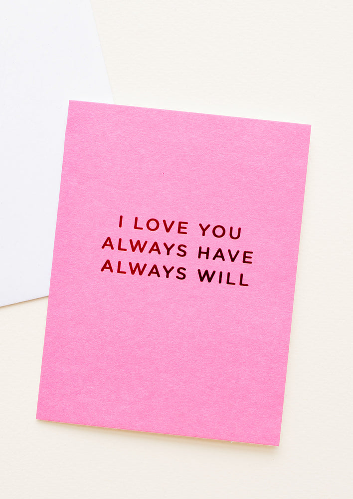A bright pink greeting card with "I love you always have always will" in red foil.