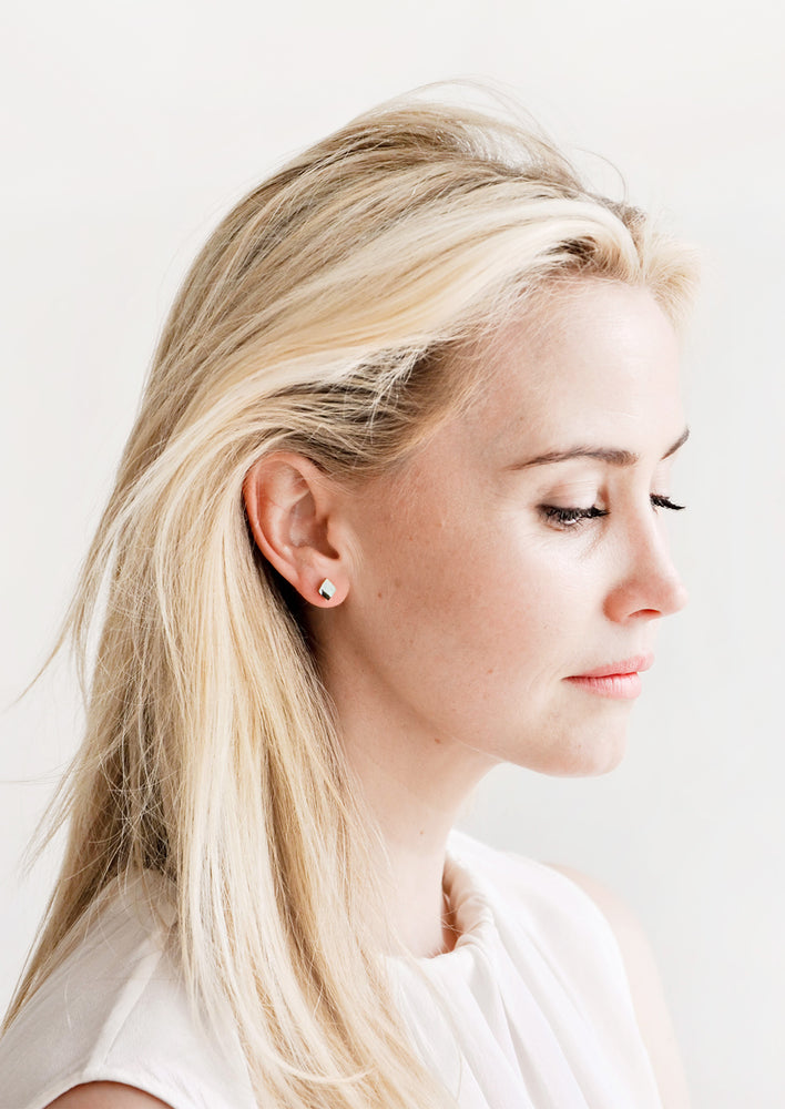 Blonde model wearing diamond shaped stud earrings.