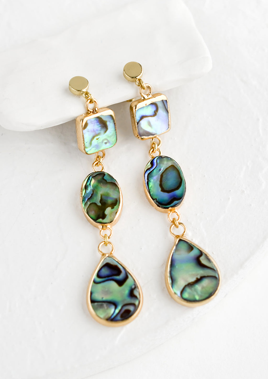 1: A pair of gold drop earrings with three geometric shapes in abalone shell.