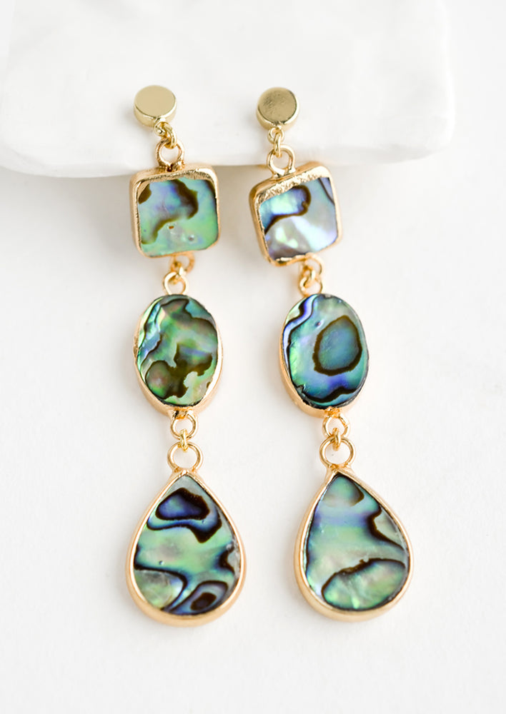 A pair of gold drop earrings with three geometric shapes in abalone shell.