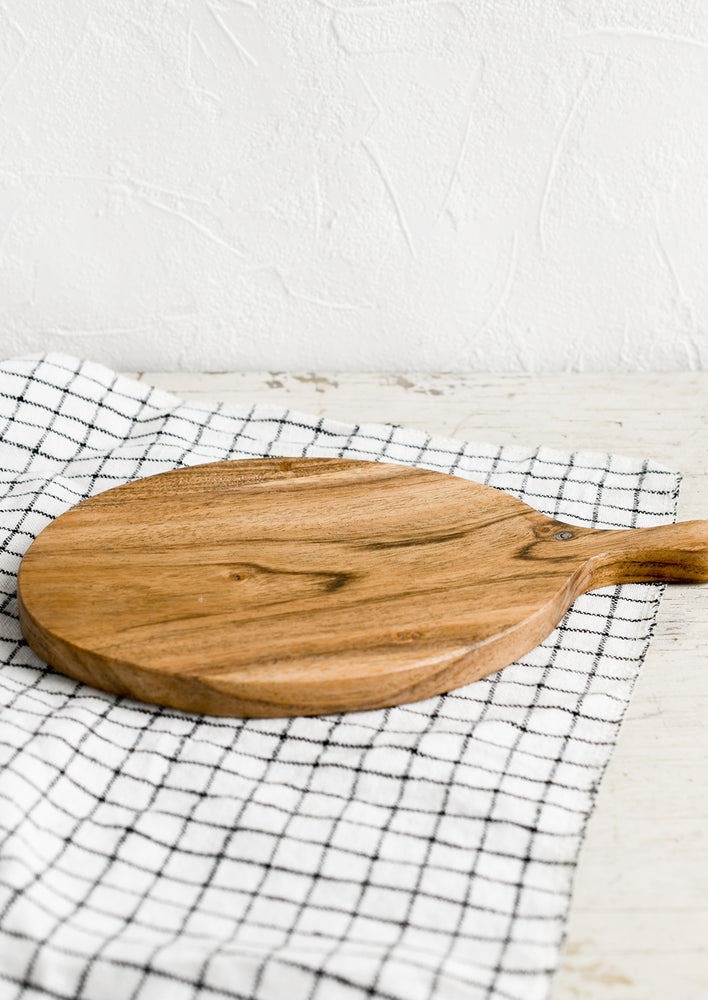 2: An oval shaped paddle-style cutting board in acacia wood.