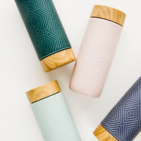1: A scattered grouping of tall ceramic travel tumblers with tonal geometric patterns