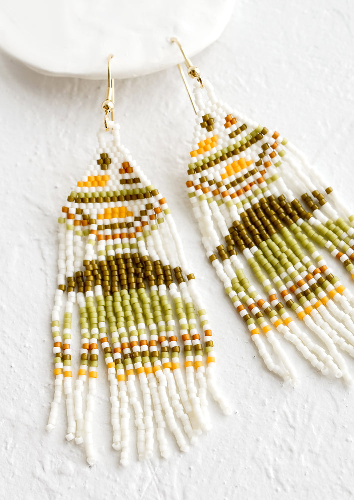 1: White beaded earrings with design in shades of green, brown and yellow.