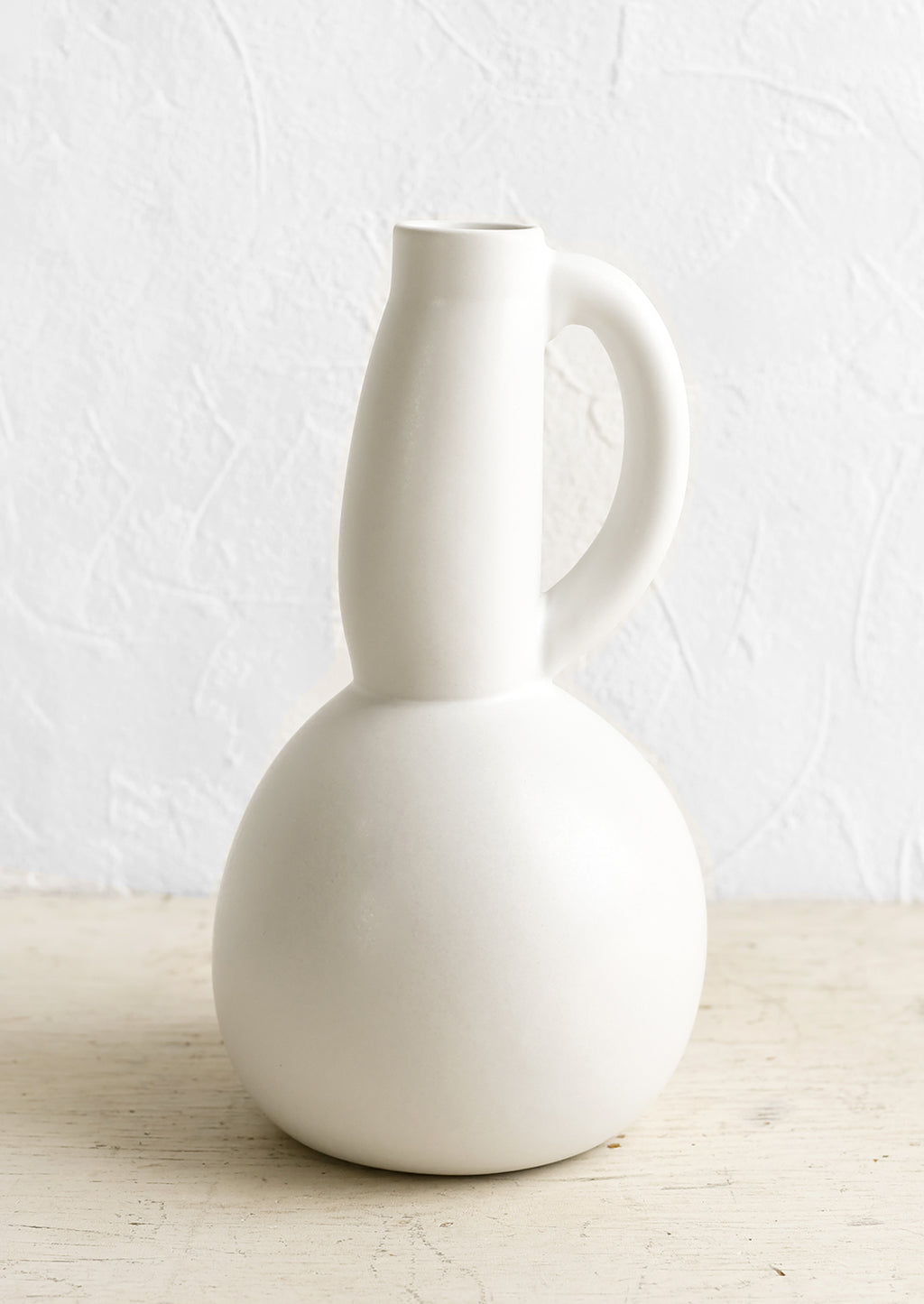 1: A white ceramic pitcher with curved, voluptuous silhouette.