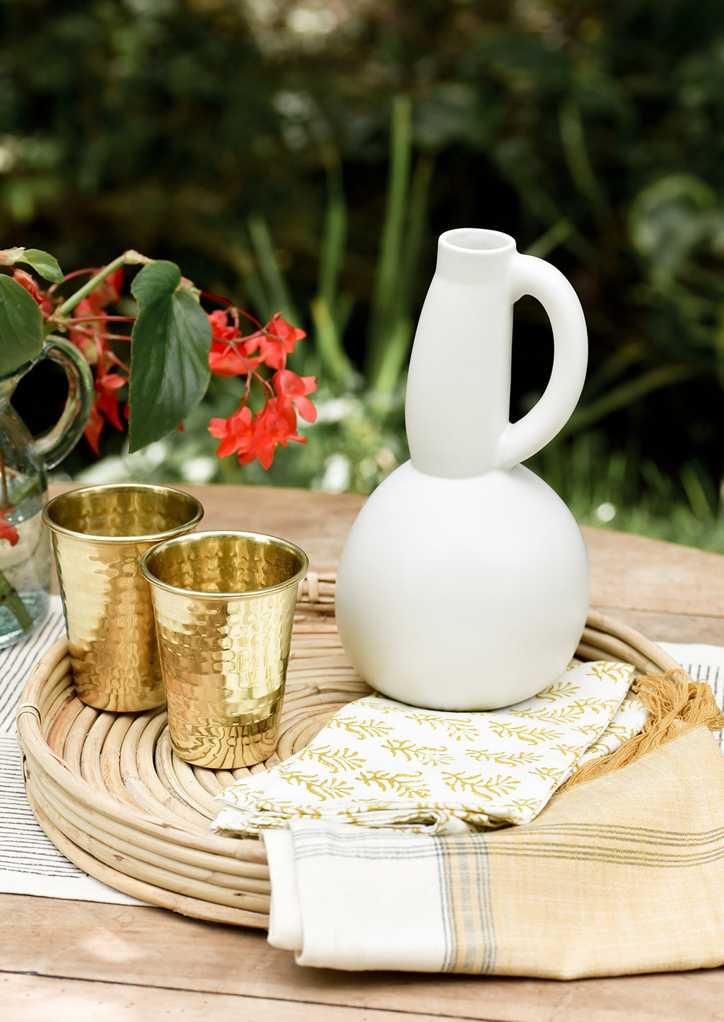 2: A table setting with ceramic pitcher and brass cups.