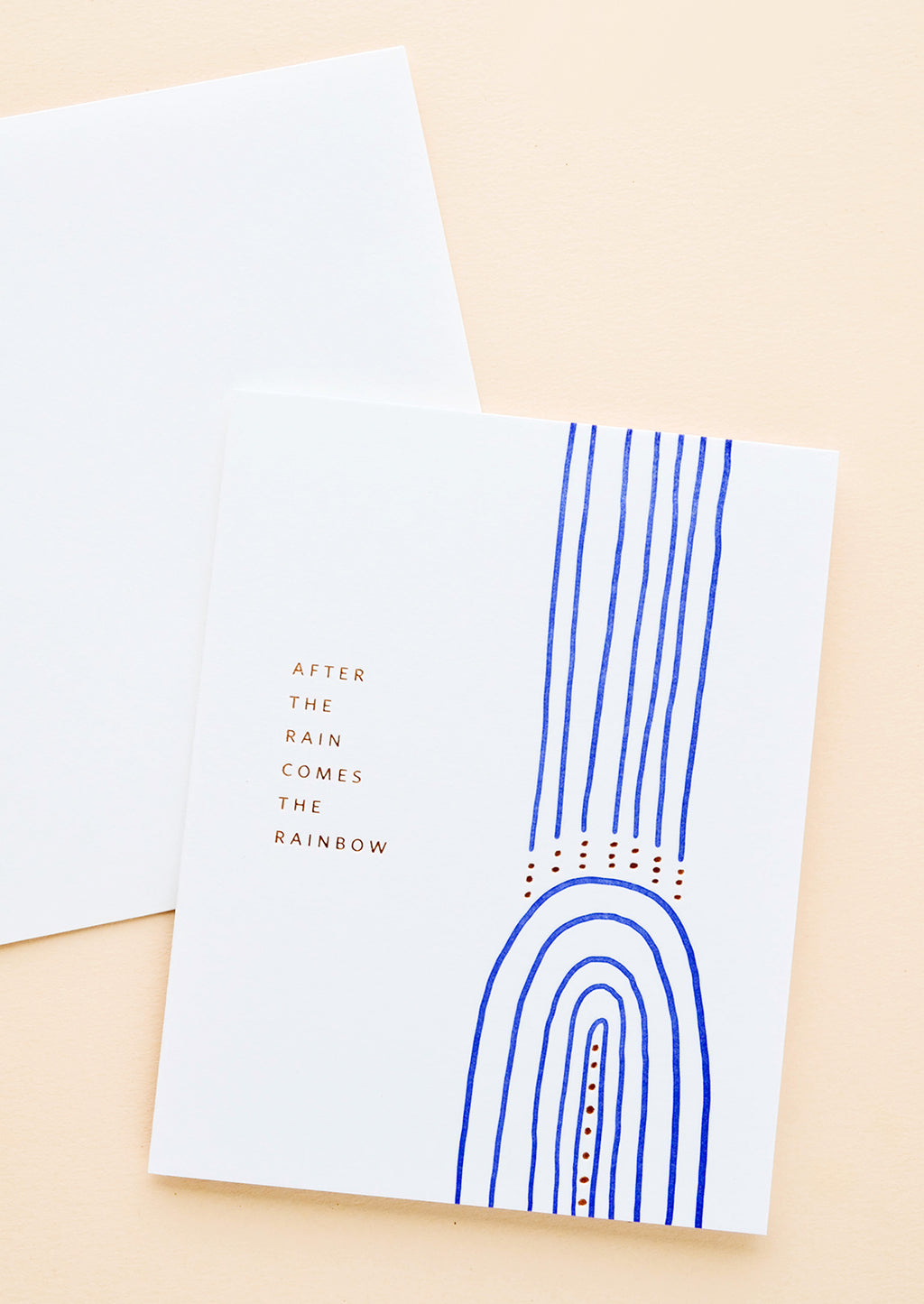 1: White greeting card with cobalt blue rainbow and gold text reading "After the rain comes the rainbow"