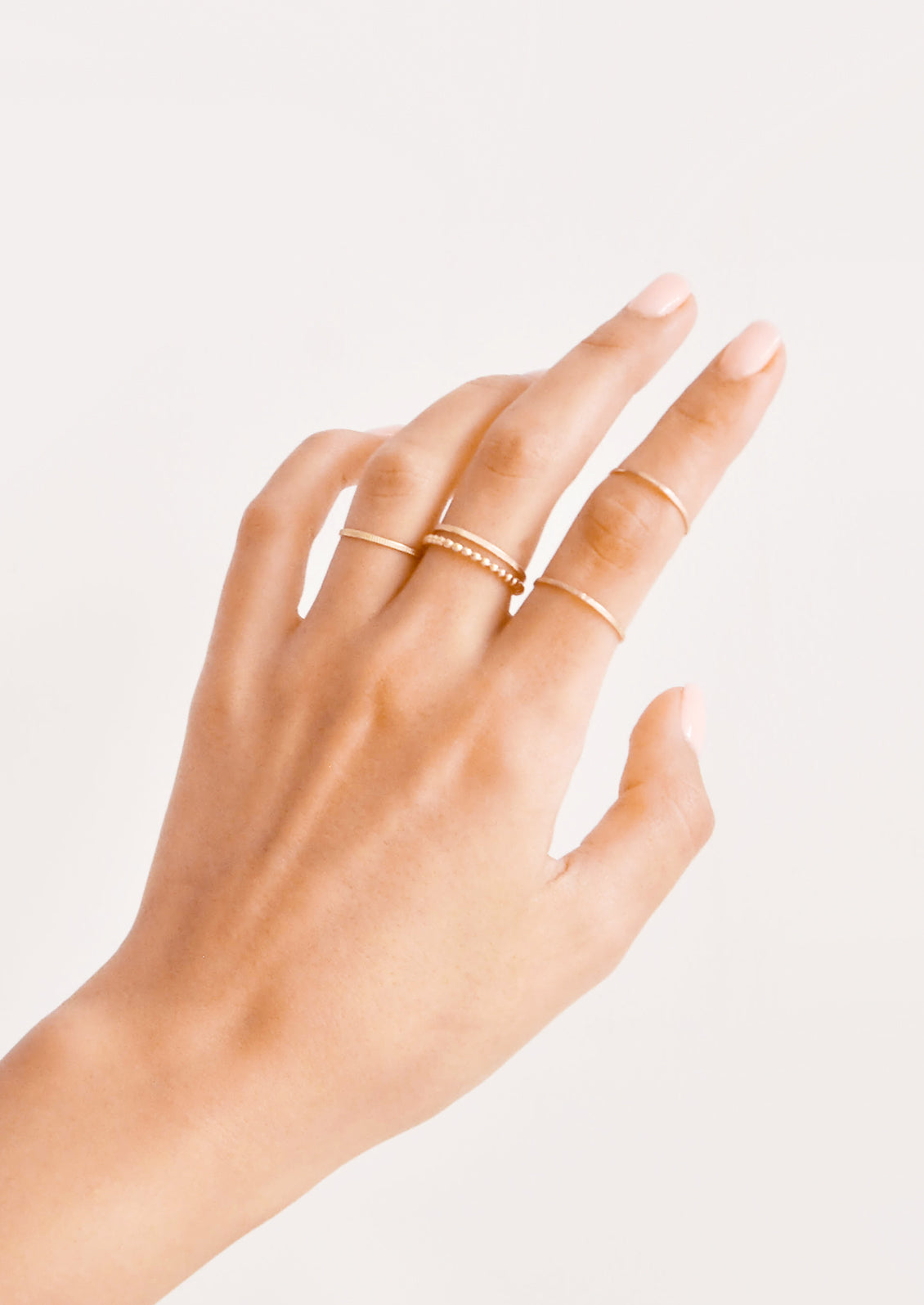 Model shot showing hand wearing stacking gold rings.