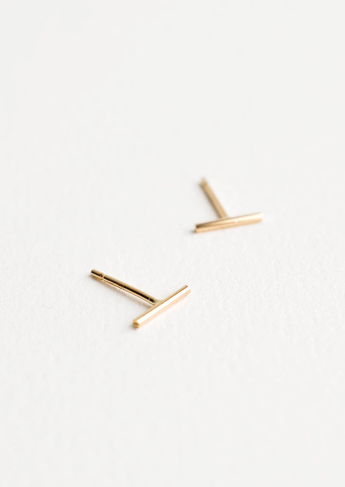 Close up of thin gold bar post back stud earrings.