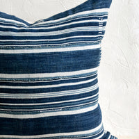 1: A throw pillow made from dark indigo fabric with white stripes and embroidery detailing.