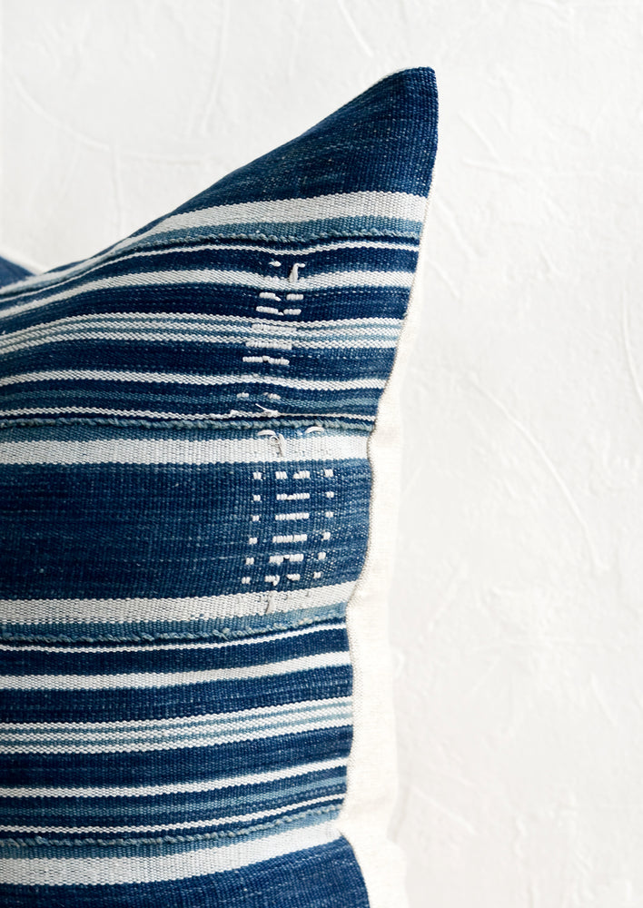 3: Embroidery detailing on a striped indigo fabric pillow.
