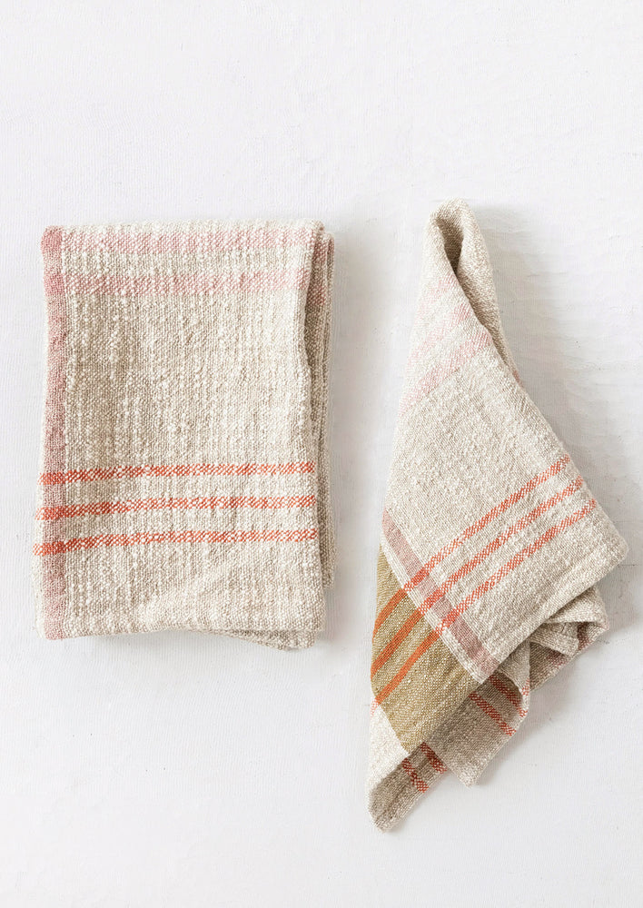 A natural tea towel with orange, ochre and pink plaid pattern.