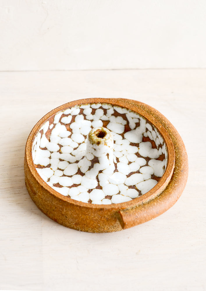 A round ceramic incense holder with white foam glaze.