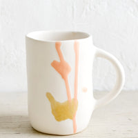 1: A tall white ceramic mug with peach and mustard glaze drip detail.
