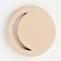 Straw: A round concrete trivet in straw color with crescent moon shaped cutout.